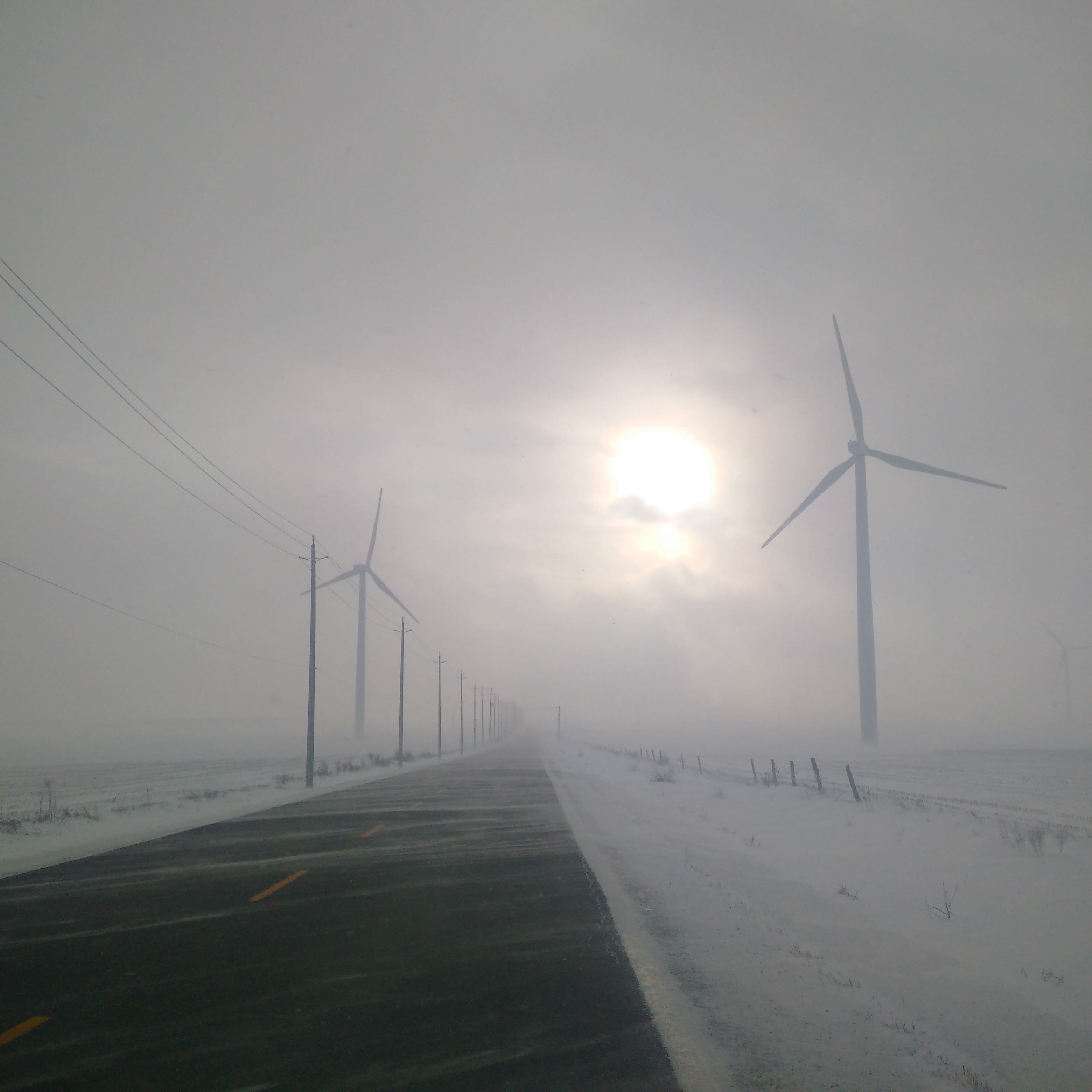 Wind turbines along a snowy road