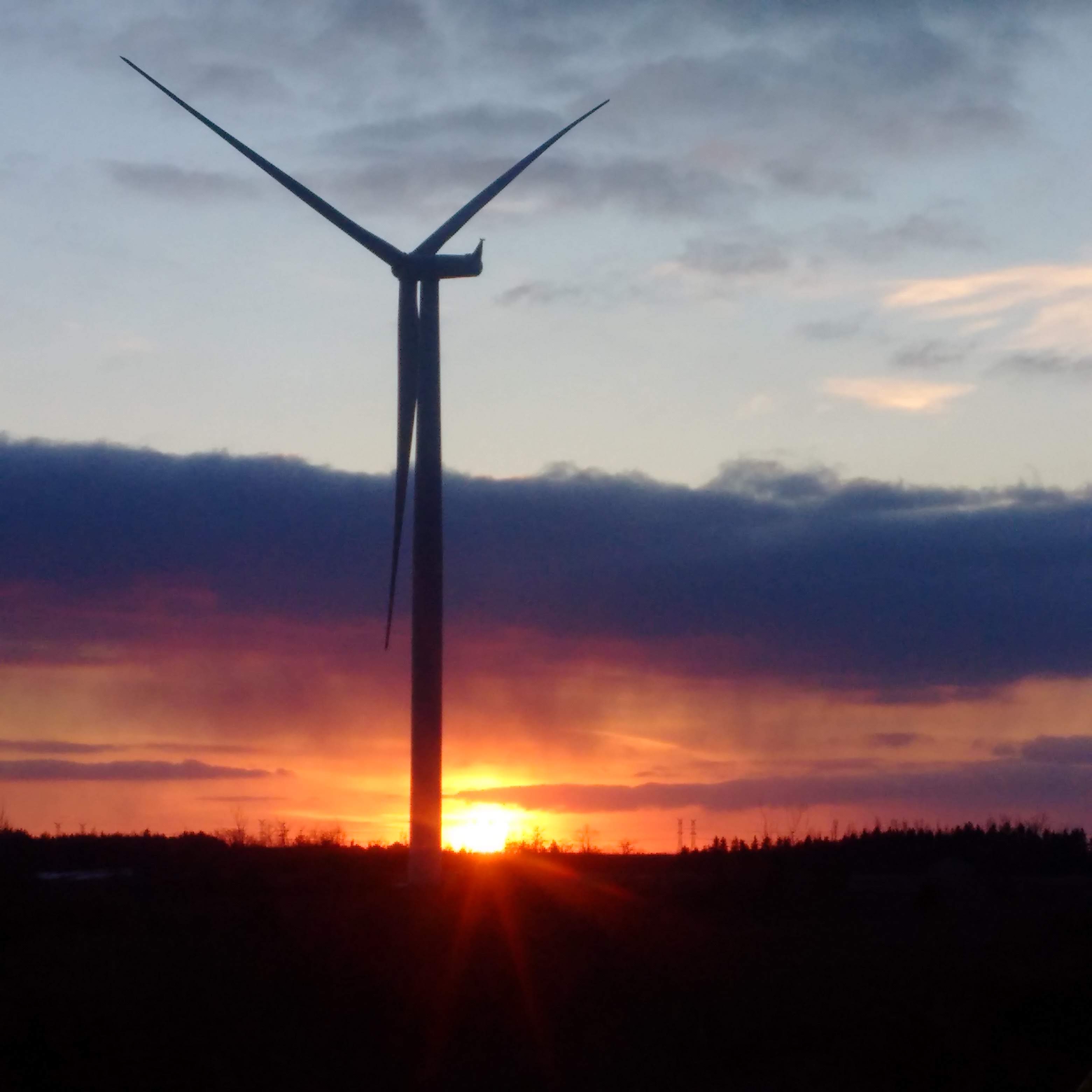 A silhouette of a wind turbine at sunset